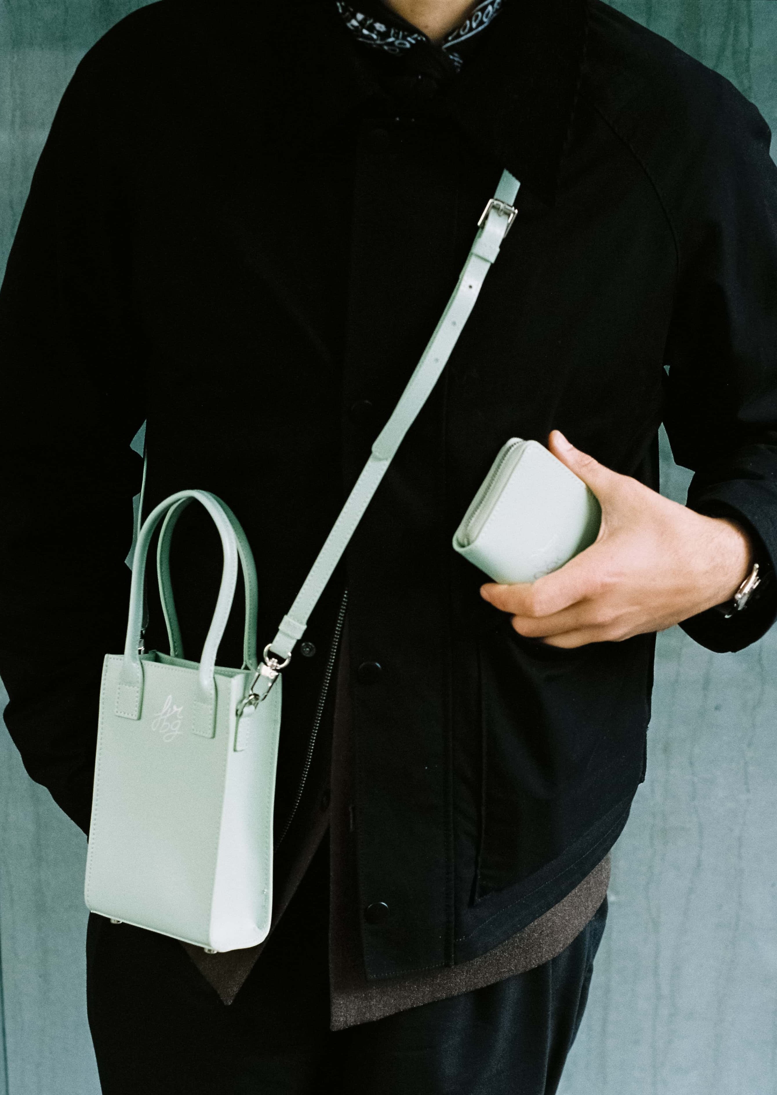 Personne en noir avec un sac et un portefeuille verts clairs