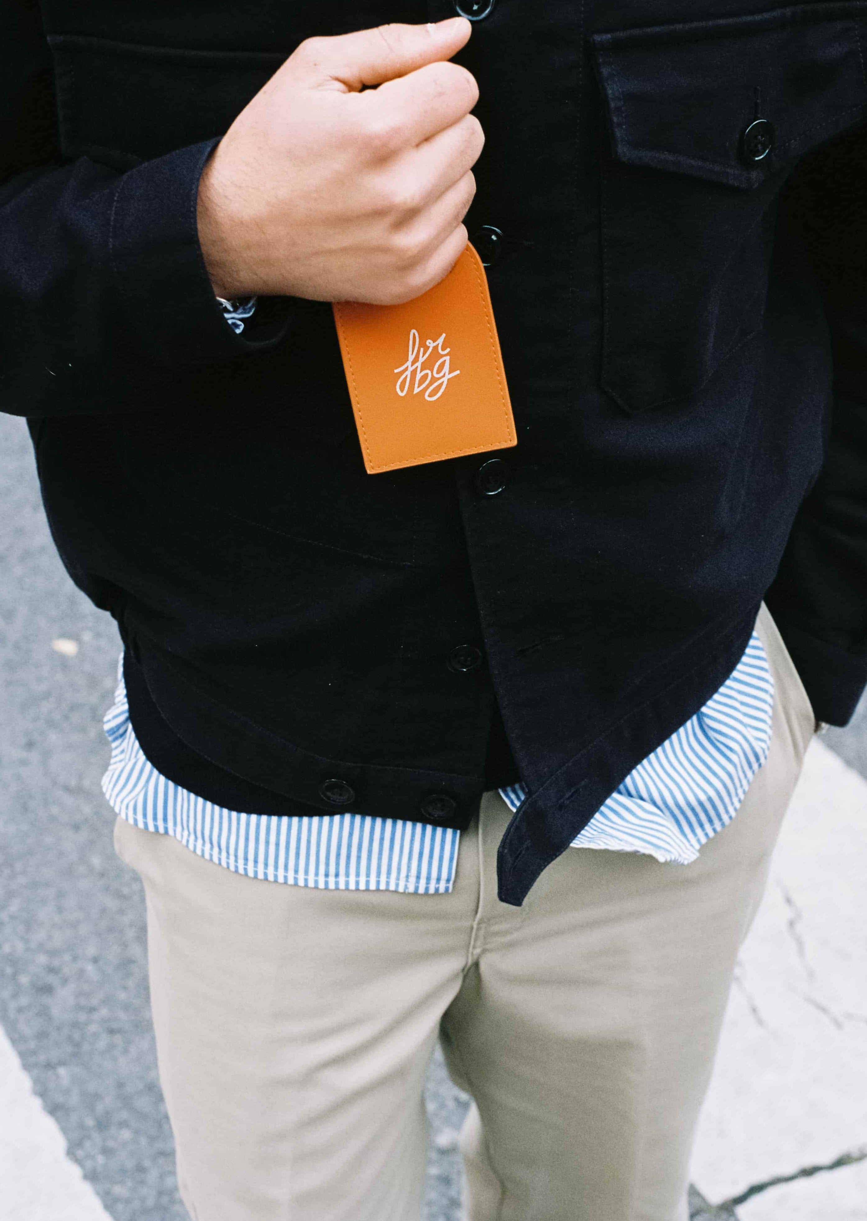 Personne en noir tenant un porte-adresse orange avec logo blanc