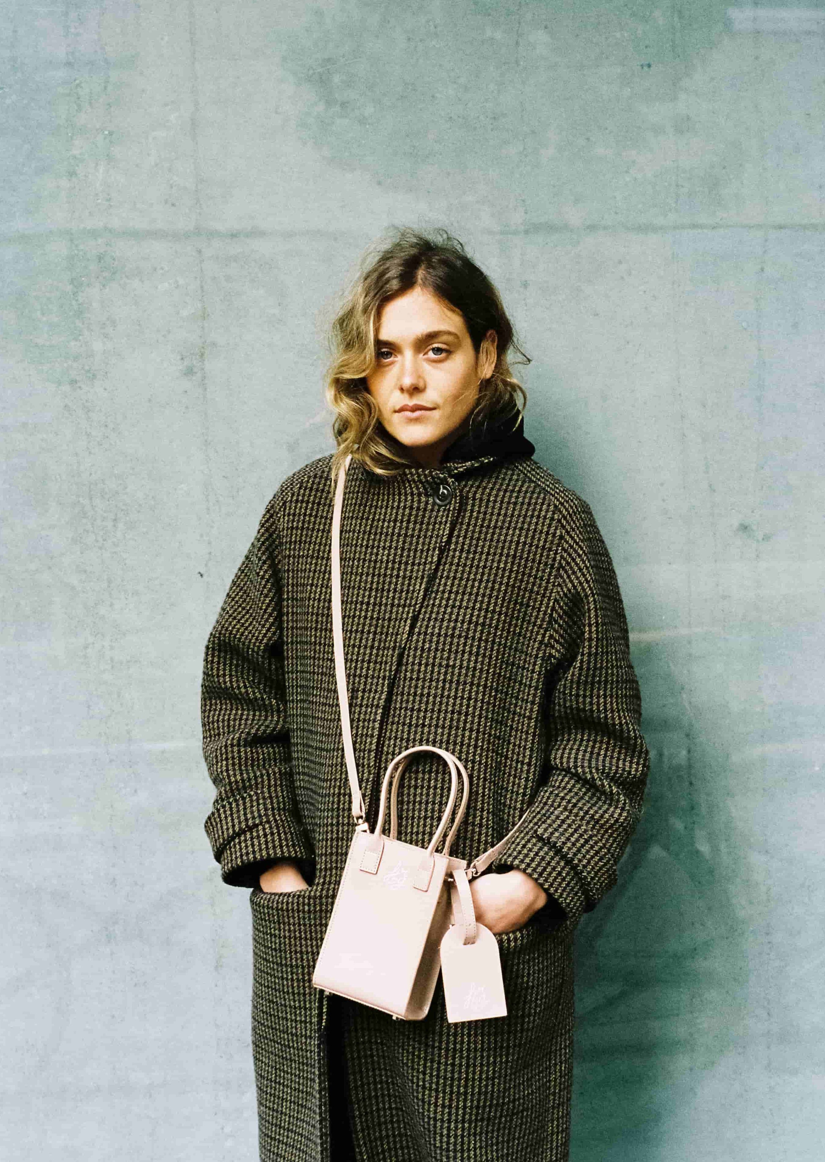 Femme en manteau vert foncé avec un sac clair