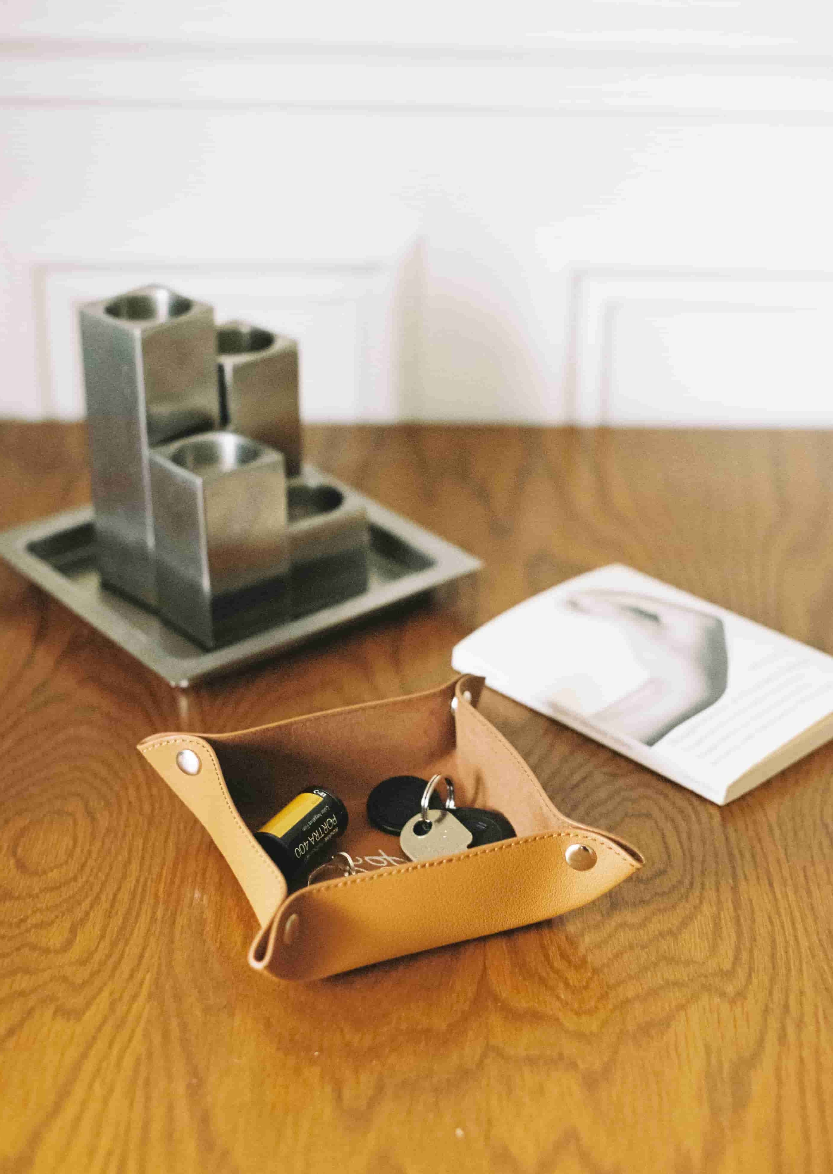 Vide-poche en cuir marron clair avec clés et film sur une table
