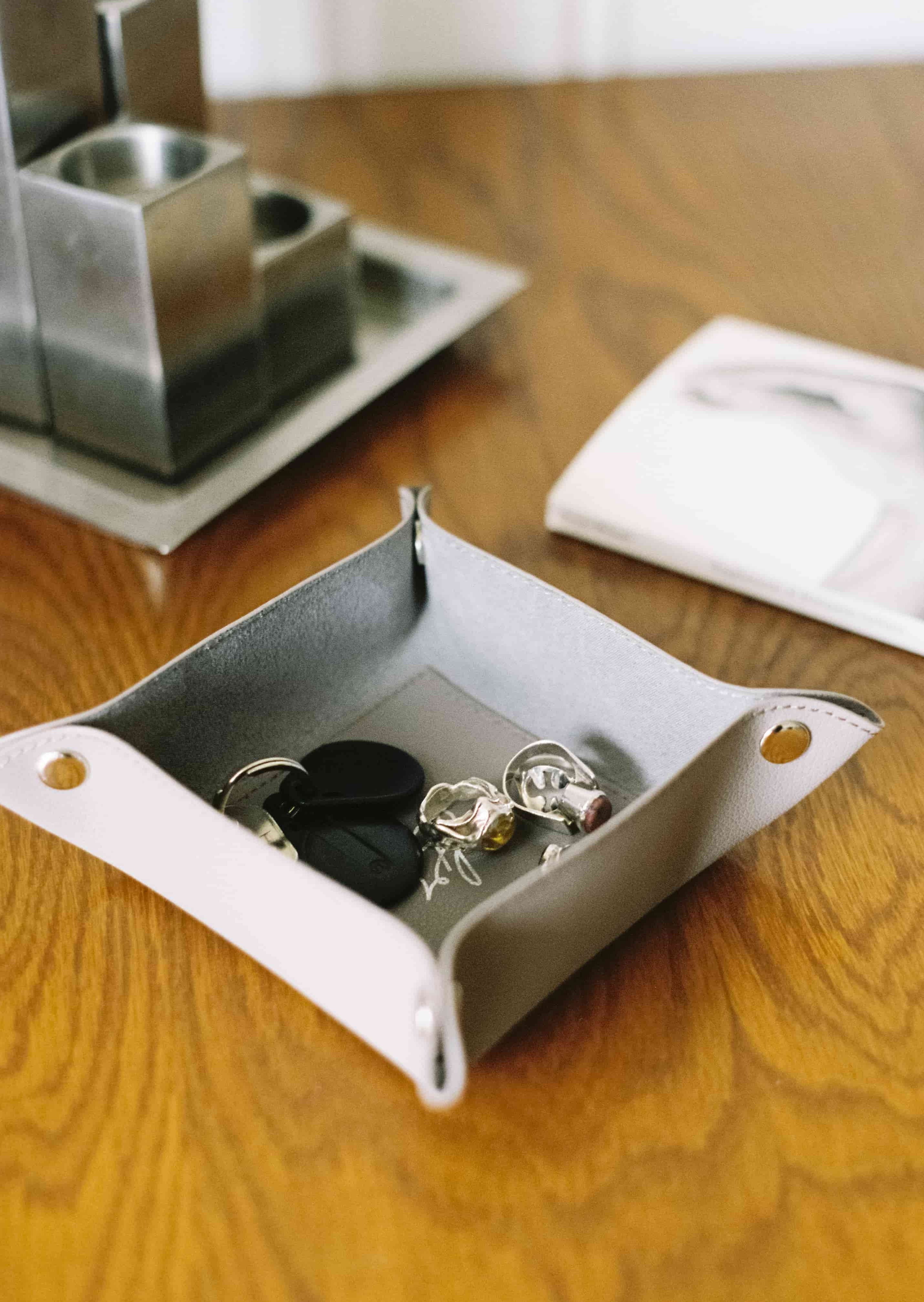 Vide-poche en cuir taupe contenant des clés sur une table