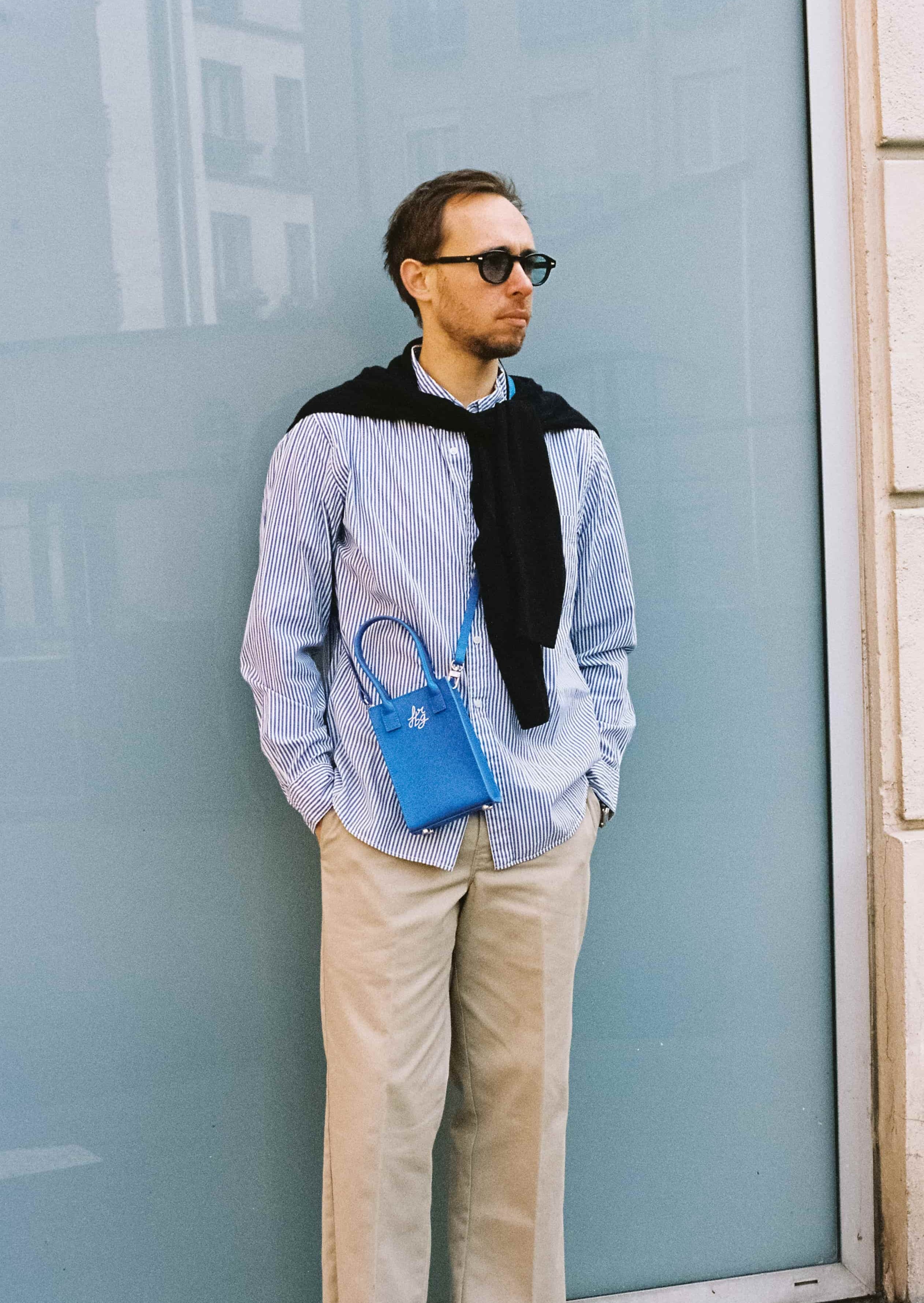 Homme en chemise rayée avec un sac bleu et lunettes