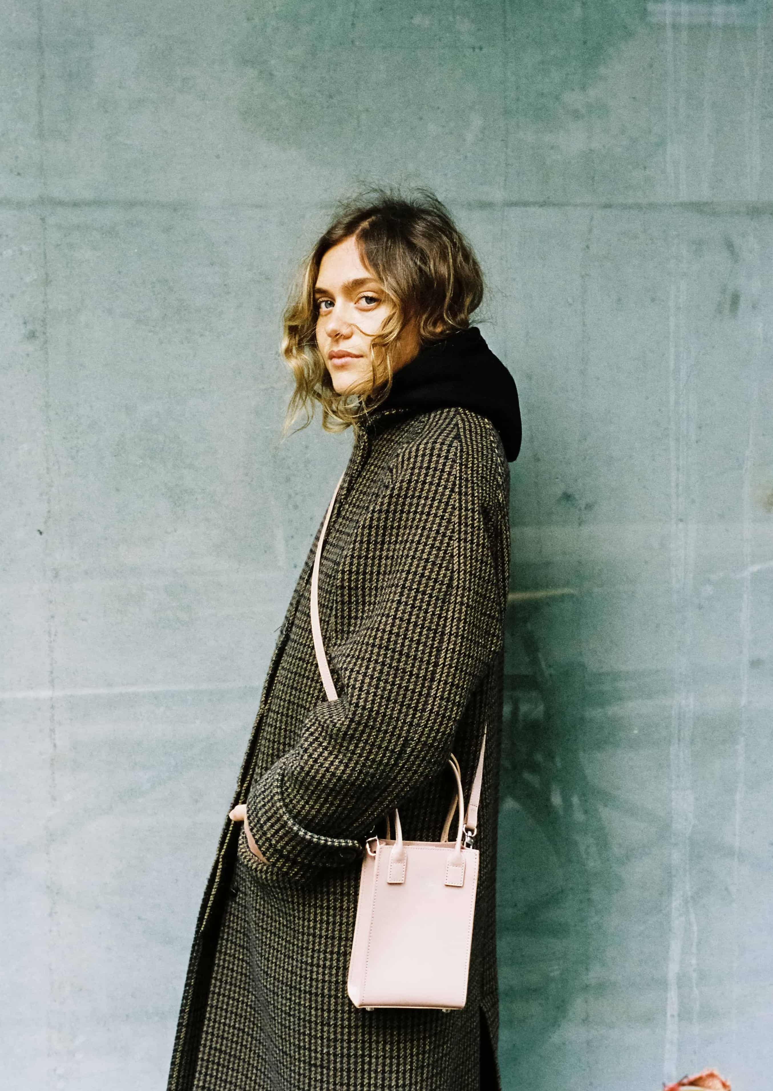 Femme en manteau avec un sac à main rose clair