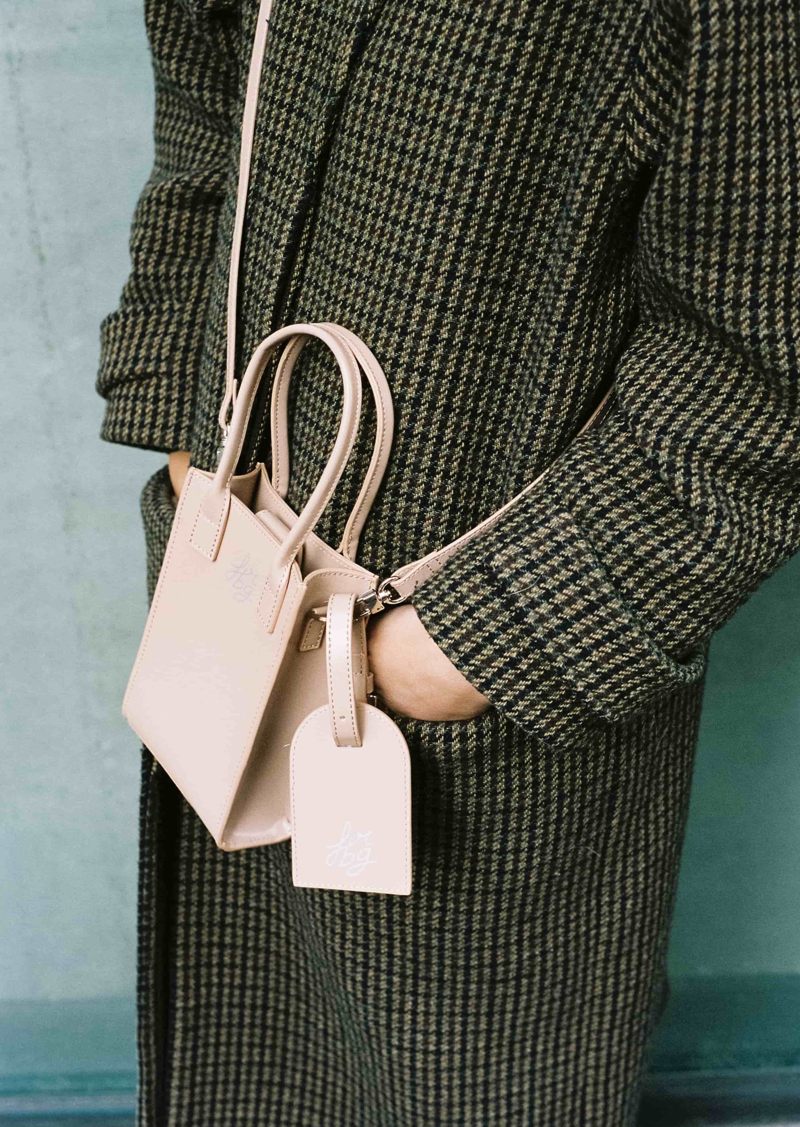 Personne portant un manteau à carreaux avec un sac rose clair