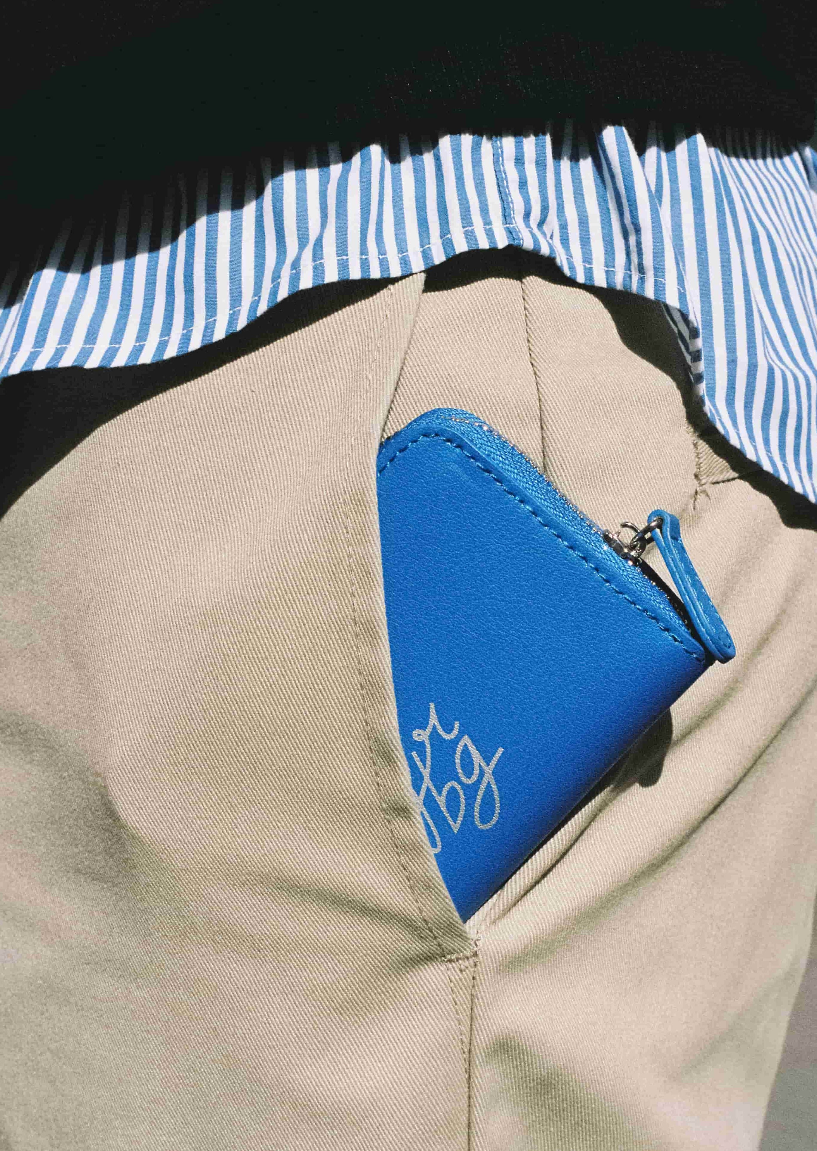 Porte-monnaie bleu dans une poche de pantalon beige