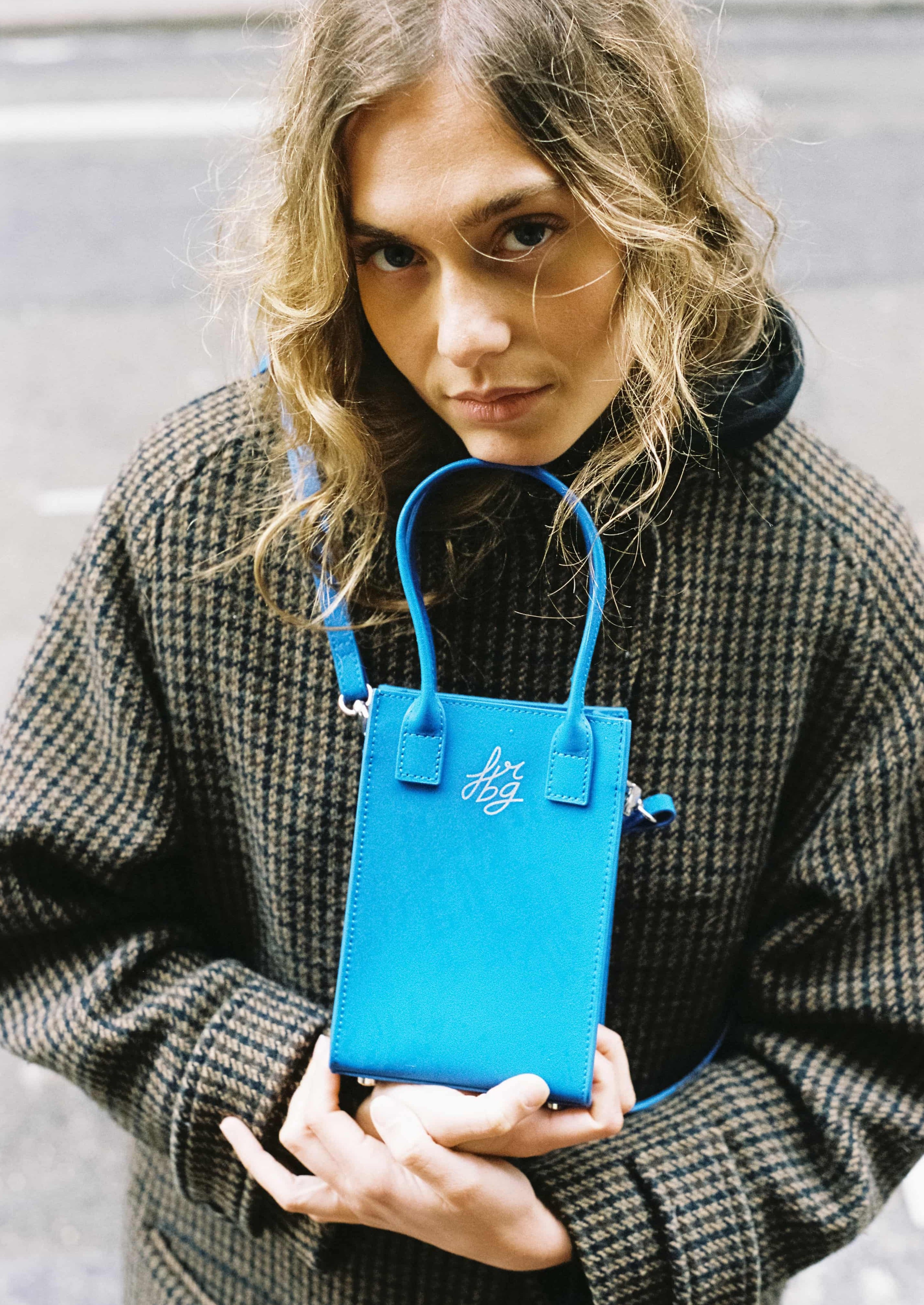 Jeune femme avec sac bleu, portant un manteau à carreaux