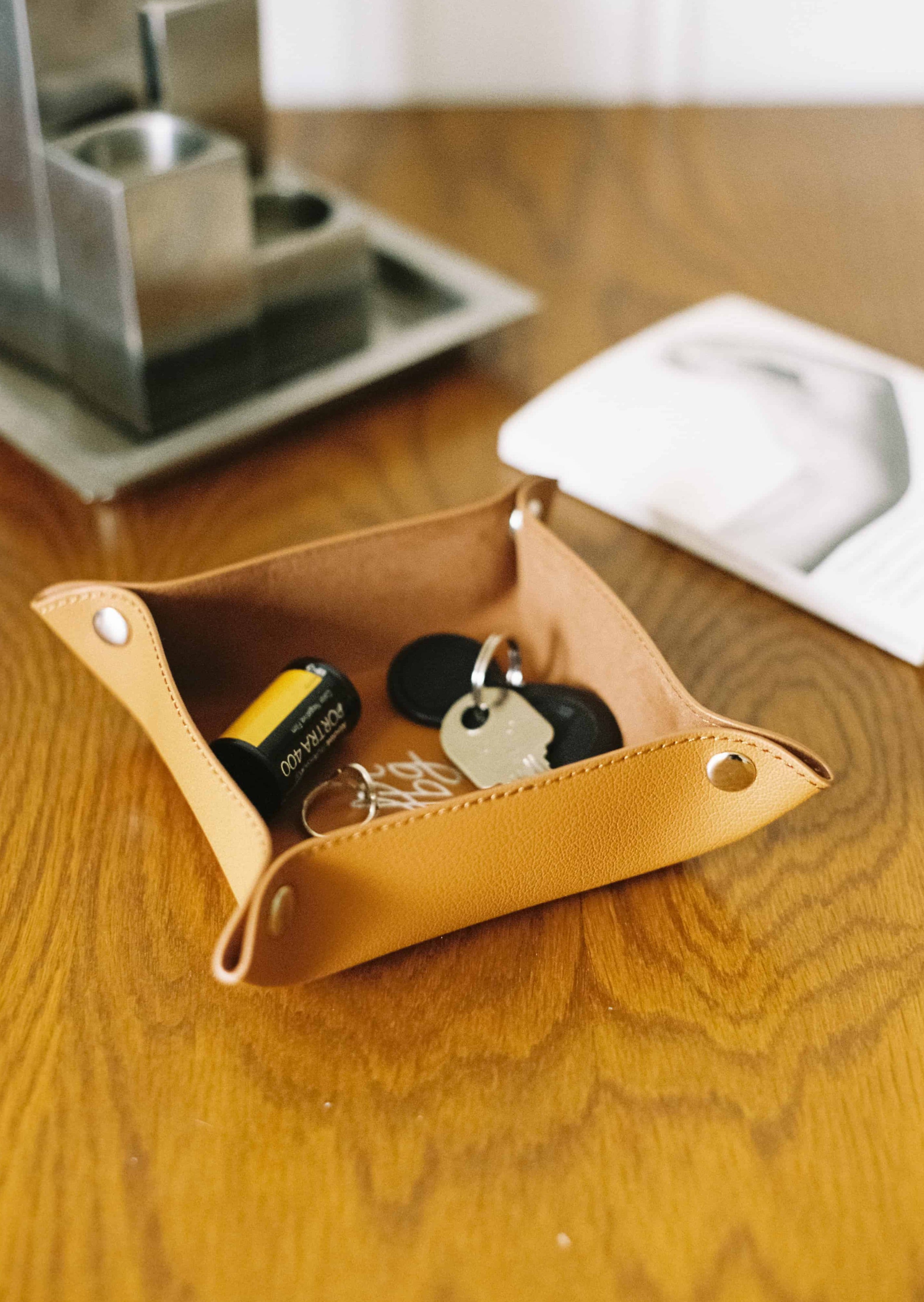 Vide-poche en cuir marron clair avec clés et film sur une table