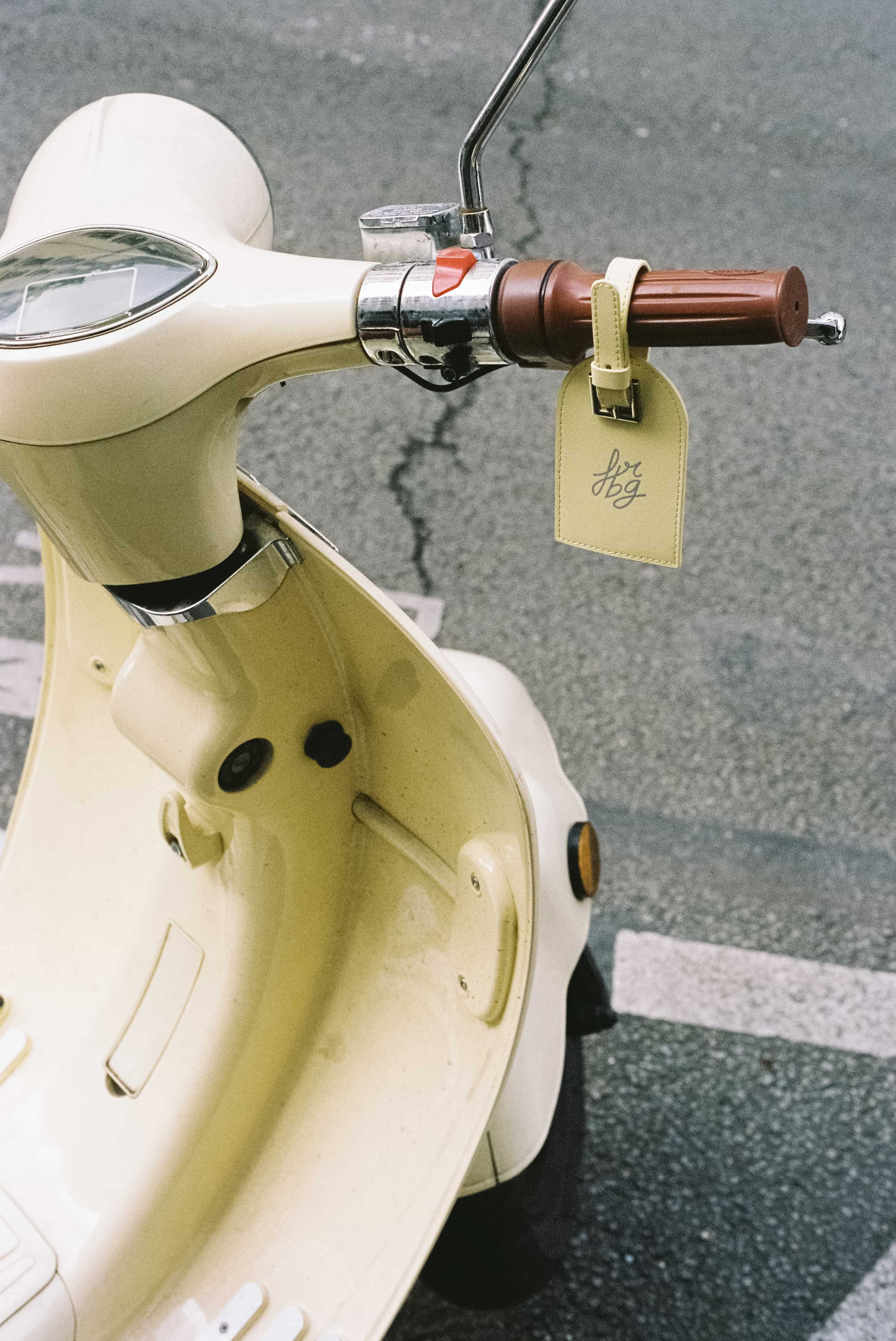 Porte-étiquette jaune pastel avec logo attachée au guidon d'un scooter