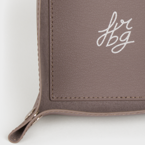 Détail d'un vide-poche en cuir taupe avec logo argenté "fbg"